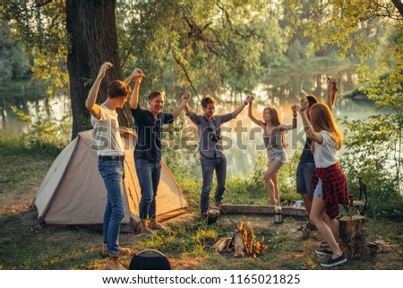 smiling hipsters are spending funny time at campsite. wonderful scenery on the background of the photo