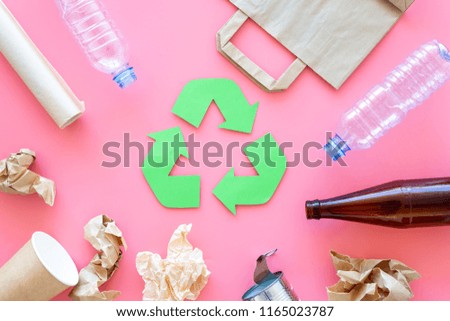 Recycling. Green recycle eco symbol. Recycled arrows sign near matherials for recycle and reuse on pink background top view
