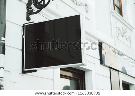 Blank square black signage on building with classical architecture and daylight. Mock up 