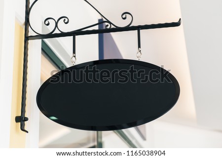 Empty black oval signage on building with classical architecture and daylight. Mock up 