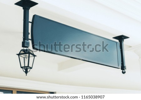Empty black rectangular signage with lantern on building with classical architecture and daylight. Mock up 