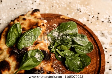 Pizza calzone with basil leaves close up