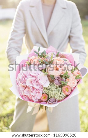 Young girl holding a beautiful spring bouquet. flower arrangement with hydrangea and garden roses. Color light pink. Bright dawn or sunset sun