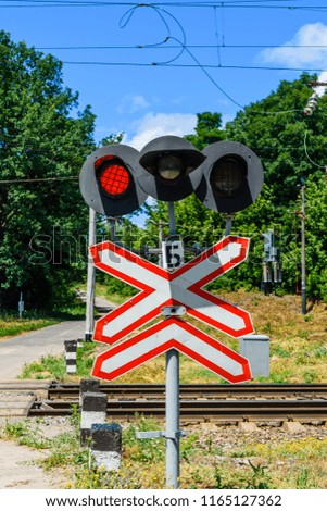 Railroad crossing sign and blinking semaphore in front of railroad crossing