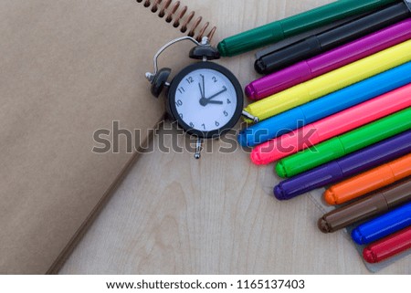 colorful felt-pens,notebook and clock on the wooden table for school or kindergarten activity time or education concept.creative ideas for child development.back to school and happy teachers day.
