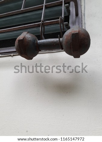 Closeup of old rust dumbbell is hanging on the louver window.