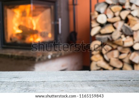 Old wooden table and fireplace with warm fire on the background.