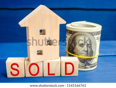 wooden house on a blue background with the inscription sold. sale of property, home, real estate. affordable housing. place for text. copy space