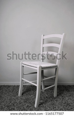 empty vacant chair in entirely gray room