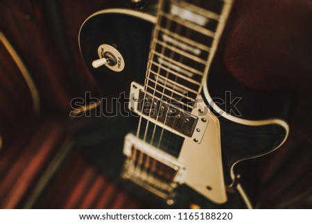 A close up shot of an electrical guitar on a brown leather chair. Music, performance and entertainment concept. Selective focus on the details.