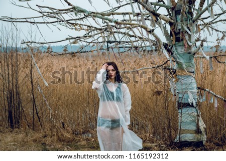 Portrait of a brunette girl in white near a tree without leaves.