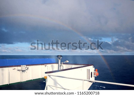 Rainbow in the ocean after rain and thunderstorms. Colorful views of the rainbow against the sky, clouds and sea horizon.