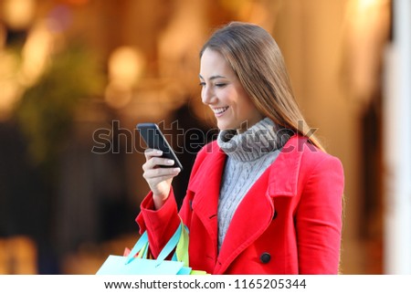 Happy shopper shopping and using a smart phone in a mall in winter