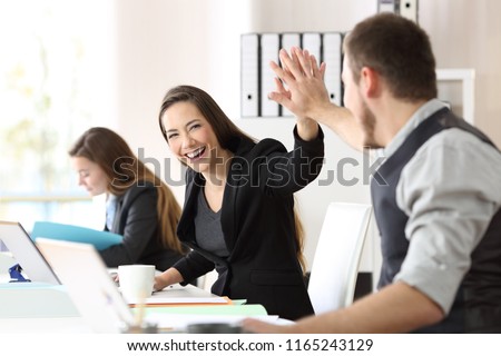 Two happy coworkers celebrating success giving five at office Royalty-Free Stock Photo #1165243129