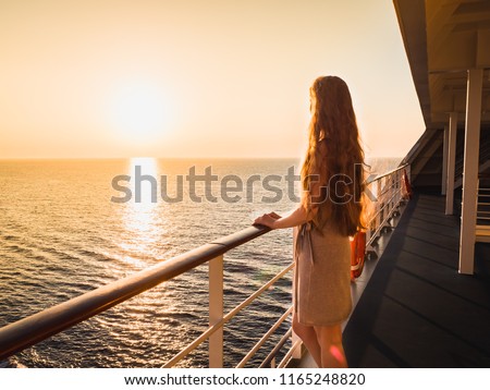 Stylish, beautiful woman on an empty deck of a cruise ship against a background of sea waves, blue sky and sunset