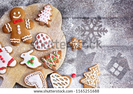 Christmas cookies of various shapes in sugar glaze on a cutting board on a brown wooden table sprinkled with flour, flat lay, copy space. Christmas composition with gingerbread men, fir-trees, rabbit