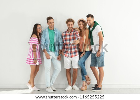 Group of young people taking selfie near white wall