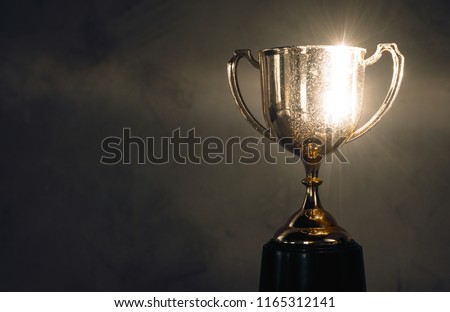 champion golden trophy placed on wooden table Royalty-Free Stock Photo #1165312141