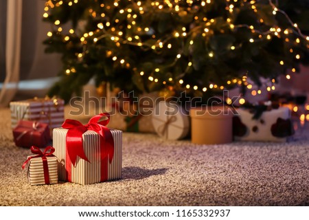 Beautiful Christmas gift boxes on floor near fir tree in room Royalty-Free Stock Photo #1165332937