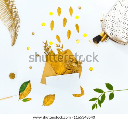 Golden Styled desk with envelope, blank card, composition of golden leaves and gold creative stuff. Flat lay.