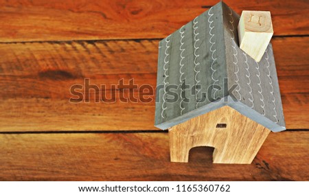 Close up on a model wooden house on plank wood background. 