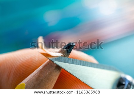 Marco picture of hand sharpening blunt pencil with art knife and cutting mat on background
