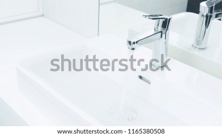 Iron shining tap with running water in white bathroom
