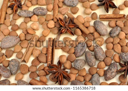 Top view of ingredients for chocolate, cocoa beans, cinnamon, anise, apricot beans on natural wood background for graphical resources