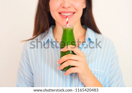 Diet nutrition with detox juice. Healthy woman posing with fresh juice bottle of green detox smoothie. Closeup of happy beautiful fit girl with fresh juice