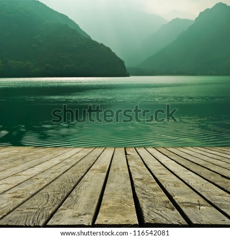 Mountain lake and flowing river with a wooden bridge Royalty-Free Stock Photo #116542081