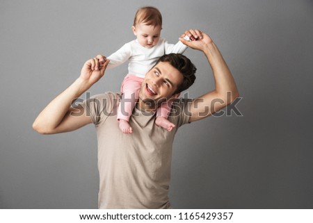 Photo of happy father man carrying his newborn baby on neck isolated over gray background