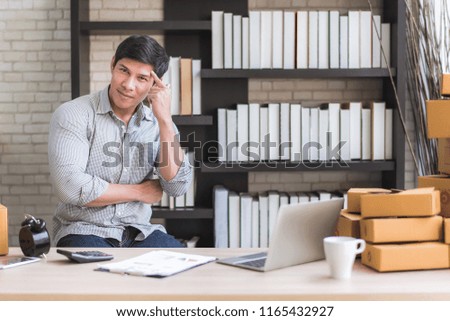 Happy young Asian man at office of his business online shopping.