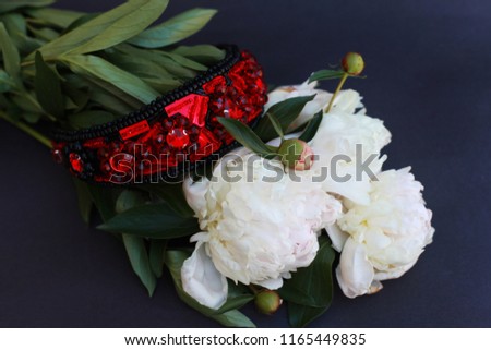 handmade embroidered with black beads and red gemstones hairband, women accessory, lying on a bunch of white flowers peonies, bride's details, wedding hair accessory