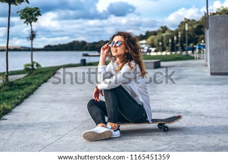 Pretty girl with curly hair with skateboard in the park