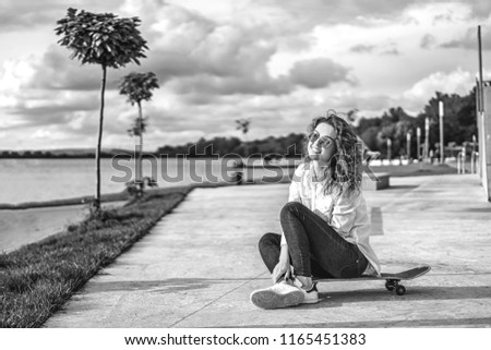 Pretty girl with curly hair with skateboard in the park
