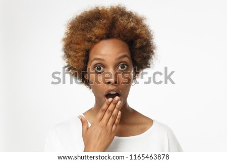 Close up photo of young african american woman isolated on gray background dressed in blank white t shirt, covering mouth with hand, experiencing deep astonishment 