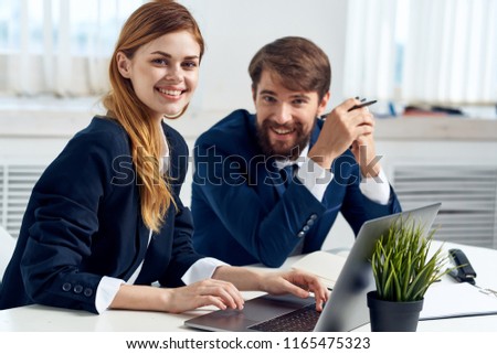 beautiful woman and man in working uniform are sitting at the table in the office                             