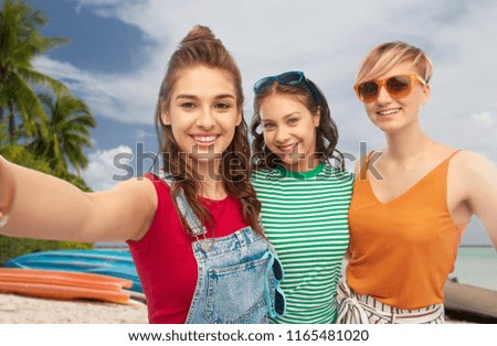 travel, summer holidays and leisure concept - group of happy female smiling friends in sunglasses taking selfie over tropical beach background in french polynesia