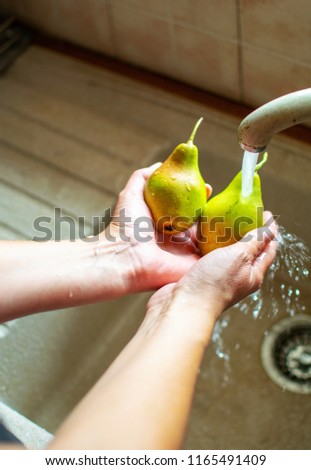 Image shows woman's hands washing pears under the water. 