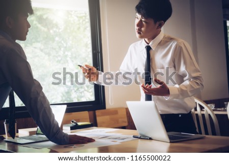 Asian business executives arguing with caucasian superior in office. Two concentrated business partners quarreling in offce on meeting
