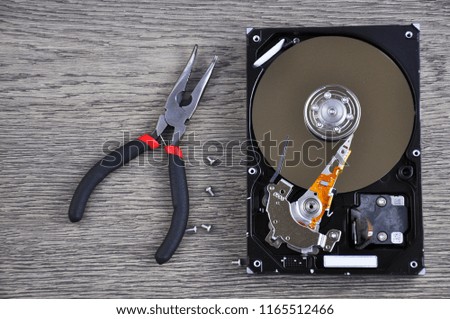 Hard drive and repair tool on wooden table close up 