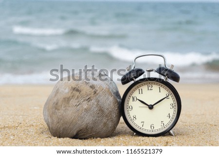 Black bell clock on beach sand and old coconut fruit