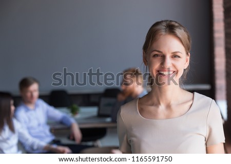 Portrait of smiling millennial worker posing for company photoshoot at business meeting in office, happy beautiful female employee look in camera making picture during teambuilding in boardroom