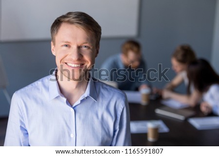 Portrait of smiling middle-aged male employee posing during company team meeting in boardroom, confident happy businessman looking in camera, making picture for corporate catalogue during briefing