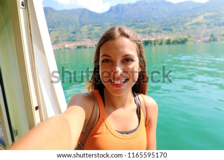 Selfie photo of young model woman on travel cruise vacation in orange tank top enjoying the evening on getaway holidays. Happy traveler vacations in Italy. 