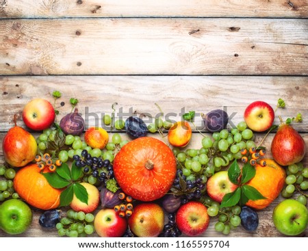 Thanksgiving background with autumn pumpkins, fruits and fall leaves on wooden table. Top view, autumn concept with copy space.