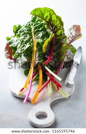 Various different coloured chard leaves on a gray surface