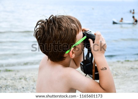 Boy taking a pictures at the beach with  retro camera 