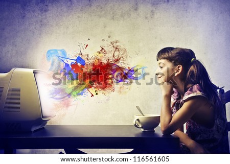 Child, during the breakfast, watching a TV from which come out of the colors