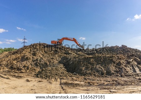 Orange excavator loads the land on a construction site


